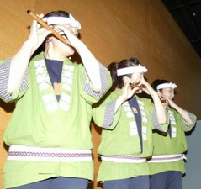 手ぬぐいハチマキと緑色の法被を着た3名の女性が篠笛を吹いている写真