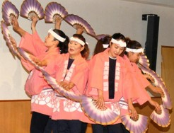 桃色の法被を着て手ぬぐいを巻いた数名の女性が背中合わせになり扇子を持って仙台すずめ踊りをしている写真