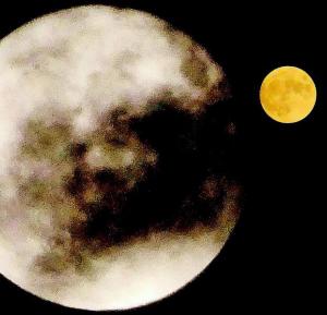 一部雲がかかっている大きな丸い月のような物とその横に小さな黄色い満月のような物が一緒に写っている写真