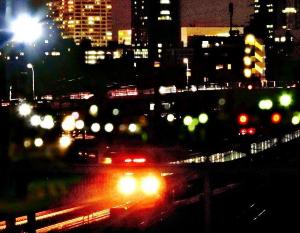 暗闇の中を走る電車とその奥に広がる街の夜景を写した写真