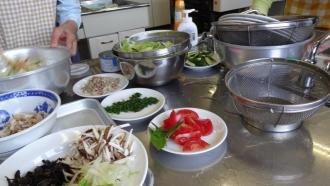 トマトやねぎ等様々な食材が調理台に並んでおり、調理の準備がされている様子の写真