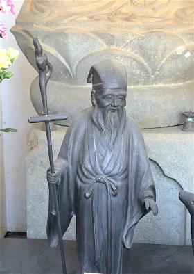 右手で杖を持ち、長いひげが生えている寿老人の石像の写真