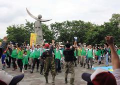 緑色のTシャツを着たイベント参加者の方々が集まりみんなで右手のこぶしを高く上げている写真