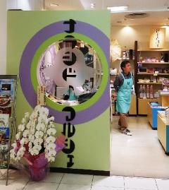 ナラシド♪マルシェと書かれた店構えと、傍に胡蝶蘭が置かれて、店内をエプロンをつけた男性が歩いている写真