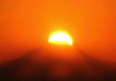 富士山頂に太陽が重なる瞬間、あかね色の太陽が光を放っているダイヤモンド富士の写真