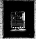 暗いトンネルのような奥に長方形でかたどられた窓が見える白黒写真