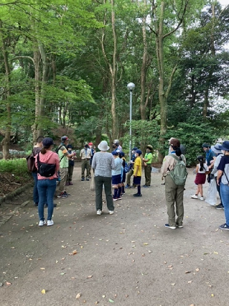 参加者達が、公園の樹々が植えられた場所に集まっている写真