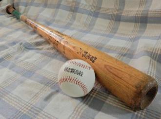 布に置かれた木製のバットと野球ボールの写真