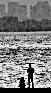 茜浜で座っている人、その横に立っている人のシルエットを写した白黒写真