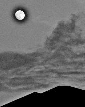 満月の下に2つの山が重なって写っている白黒写真