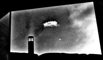 長方形の窓から、左側に煙突のような物と、中央に雲が1つ浮かんでいる白黒の風景写真