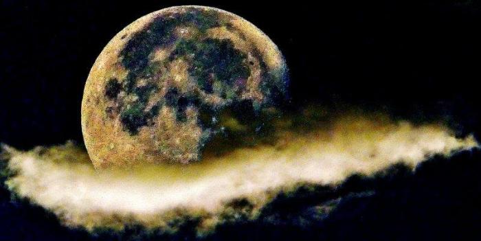 暗闇に浮かぶ大きな満月の下部分に一筋の白い雲がかかっている写真