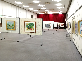 展示パネル、壁に洋画が展示されている展示室の写真