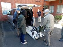 参加者が、トランク側にスロープが設置された福祉車輌で車いすの出し入れの講習を行っている写真