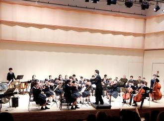 津田沼高校オーケストラ部員が舞台の上で演奏している写真