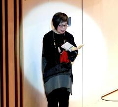 スポットライトを浴びた戸田 志香さんが舞台の上で詩の朗読をしている写真