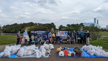 海岸清掃後、たくさんのゴミをブルーシートの上にのせ集合写真を撮っている会員のみなさんの写真