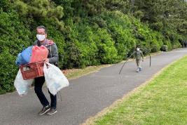 たくさんのゴミを運んでいる男性2名が道路を歩いている写真