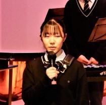 和泉鈴オーケストラ部部長の女の子がマイクを持ち挨拶をしているアップの写真
