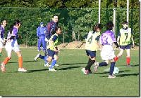 芝生のピッチでサッカーの試合をしている女子児童の写真