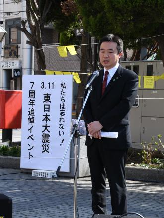 私たちは忘れない！3.11東日本大震災7周年追悼イベントと書かれた看板の横で挨拶をしている市長の写真