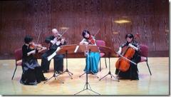 舞台の上で弦楽四重奏を演奏している4名の音楽家の写真