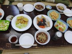 しょうゆ味のちゃんこ鍋、煮物、卵焼き、天ぷら、野菜サラダがお皿に盛り付けられテーブルに並んでいる今日のちゃんこの写真