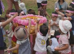 子どもたちが花のついた籠に玉を入れている玉入れの様子の写真