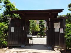 木製の両開きの門が開いている旧鴇田家住宅入口の門の写真