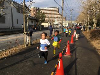 沿道を元気よく走っている七草マラソン大会に参加した子ども達の写真