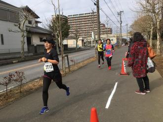 ランナーの近くで応援している人と沿道を走っている女性ランナーの写真