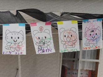 トラや熊、猫などのイラストが描かれた紙に子供たちが色を塗った塗り絵が飾られている写真