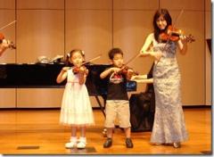 左から女の子、男の子が富澤直子さんと一緒にバイオリンを演奏している写真