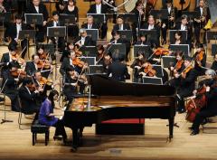 習志野フィルハーモニー管弦楽団が藤井亜紀氏のピアノと一緒に演奏している写真
