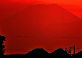 真っ赤な夕焼けにうっすら浮かぶ富士山の写真
