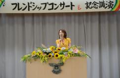 記念講演でひまわりが飾られた演台で講演をしている千葉さんの写真