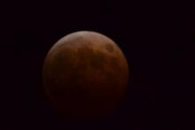赤黒い色の満月に黒い影がかかっている写真