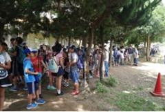 木陰で入場整理券の順番待ちをして並んでいる子供たちの行列の写真