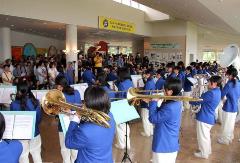 観客の方々へ向けて演奏する、青のジャケットに白のズボンで統一された習志野高校の吹奏楽部の生徒たちの写真