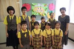 黄色いシャツに縞模様のベストやスカートを着ている習志野少年少女合唱団の子供達の集合写真