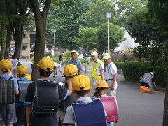 黄色い帽子を被った児童たちが登校する様子を見守っているボランティアの方々の写真