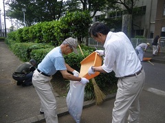 沿道で、白いごみ袋にごみを入れている清掃活動をしている方々の写真