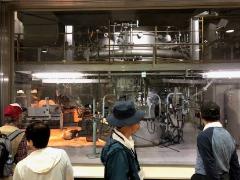 円筒状の大きな機械のある溶融炉を参加者が見学している写真