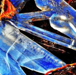 水色や青色にひかる氷の柱が輝いている水溜りの氷の造形の写真