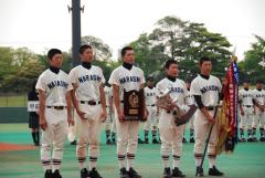 習校野球部の5名が優勝旗、トロフィー、盾を持ち並んで表彰されている写真