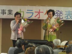 花束をもって2人で歌う女性の写真