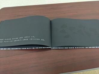 黒いページの左下に白い文字のようなものが見える開かれた本の写真