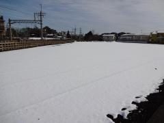 線路沿いの畑は一面、真っ白な雪が降り積もっている写真