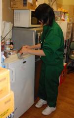 緑のジャージ姿の中学生がキッチンの掃除をしている写真