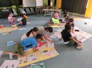 グループごとに分かれ、模造紙を広げ内容などをまとめている子供たちの写真